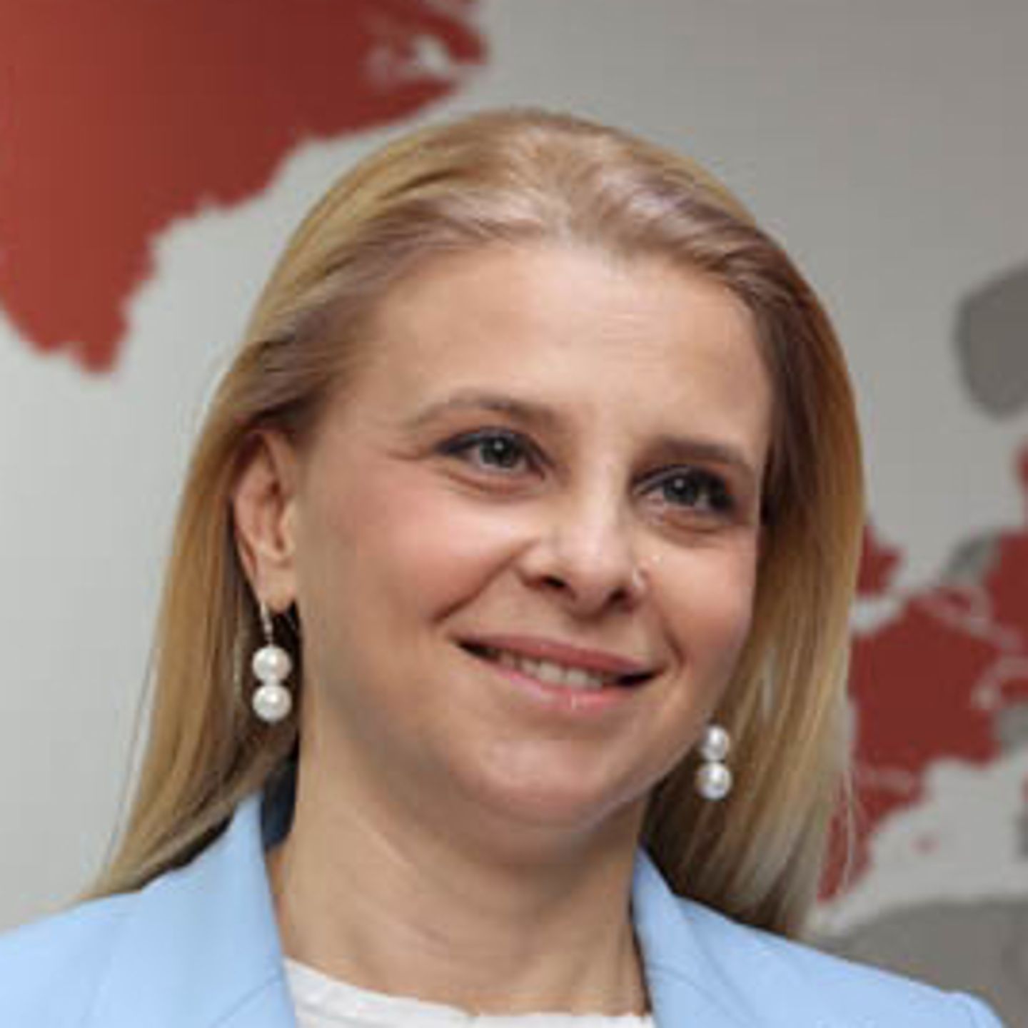 Katerina Bosevska Managing Director of EOS North Macedonia is standing in front of a world map