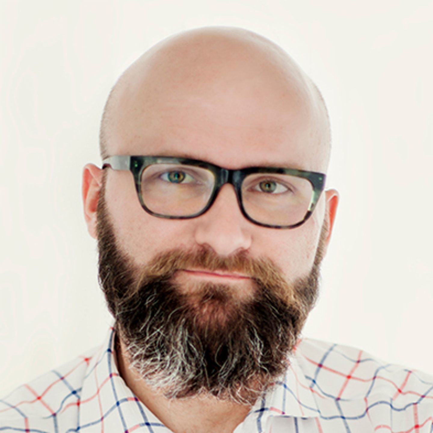 Dr. hab. Tomasz Piekot, wearing a checked shirt, leans against a wall with his arms crossed
