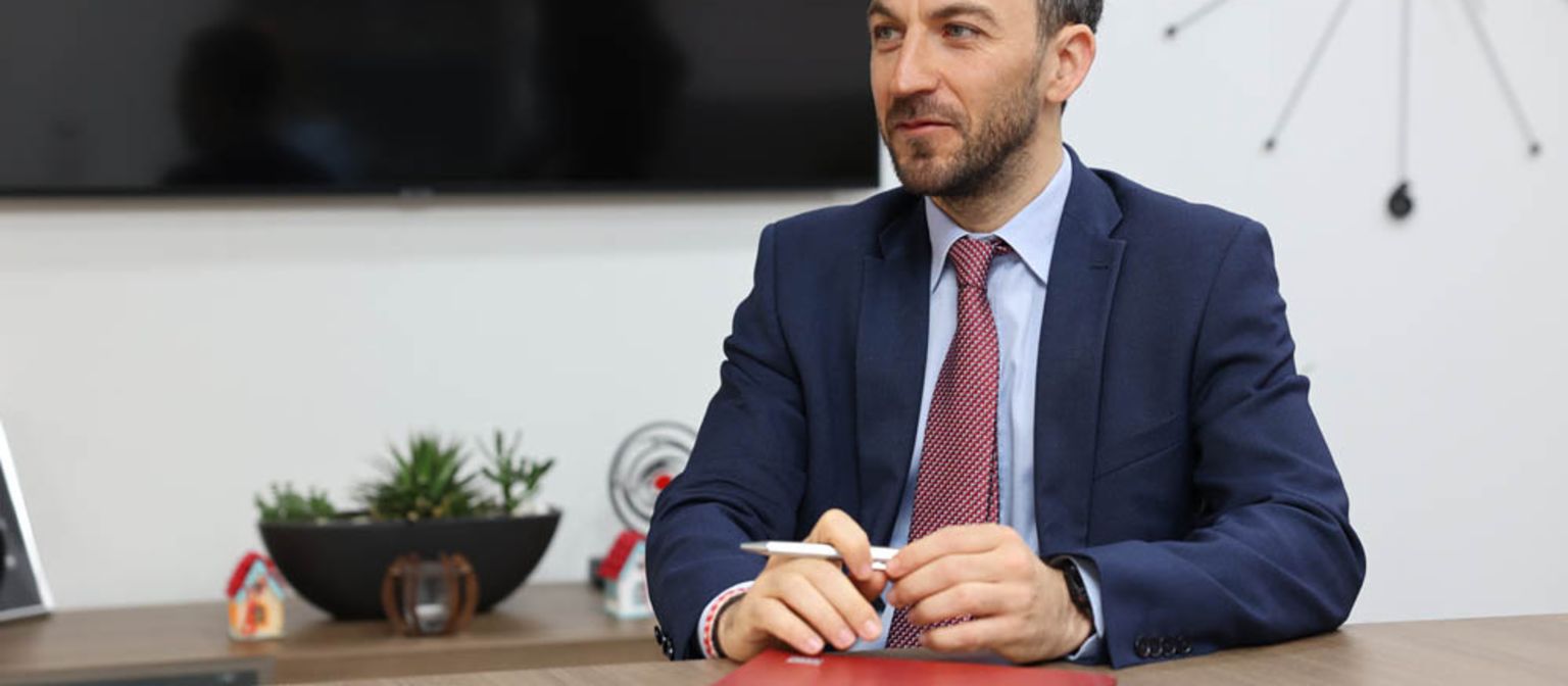 Vladislav Hadjidinev CEO of UNIBANKA is sitting at an office desk with a red folder in front of him