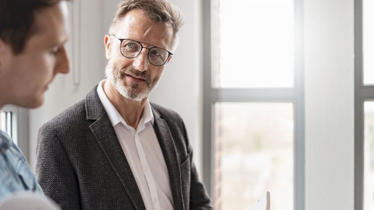 Two men in an office are discussing the results of the EOS Group's European Payment Practices 2025 study on digitization in receivables management.