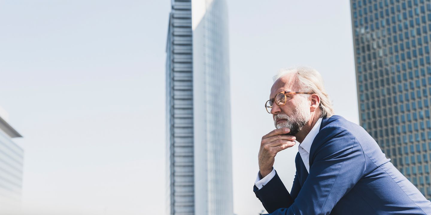 Debt collection outsourcing: Businessman looking pensive in the middle of a business district.
