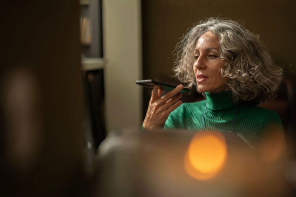 A woman holding a mobile phone is talking to AI.