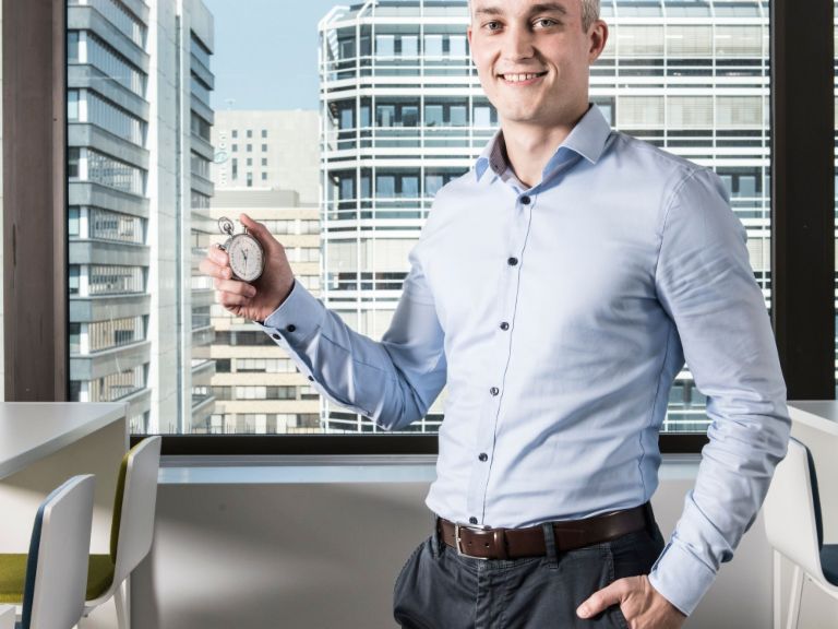 Data training: A man stands in an office holding a stopwatch