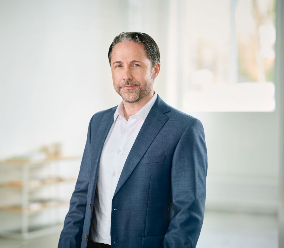 Portrait of Marwin Ramcke, Chairman of the EOS Group's Board of Directors in a bright room wearing a dark blazer 