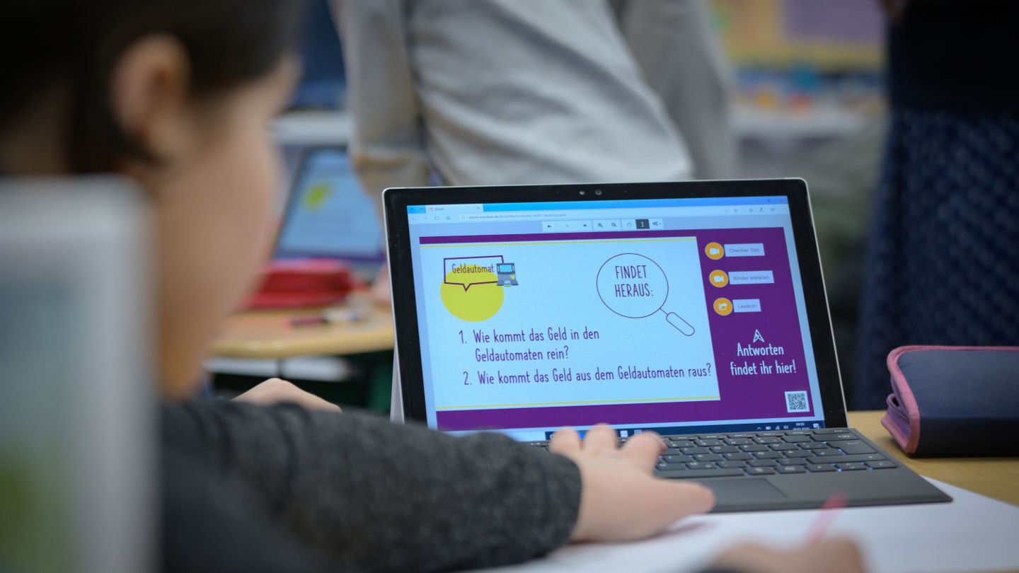 Financial education for children: Child sits at laptop and learns something about finances.
