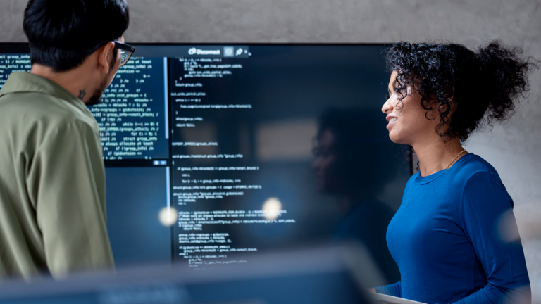 AI in debt collection: In this image, two professionals are collaboratively analyzing program code for automated processes on a large screen. The scene illustrates the practical application of Artificial Intelligence (AI) and Robotic Process Automation (RPA) in debt management – an example of digital transformation in receivables management.