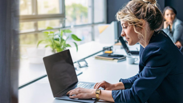 Young woman is working on a laptop in a modern office.