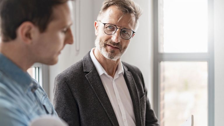 Two men in an office are discussing the results of the EOS Group's European Payment Practices 2025 study on digitization in receivables management.