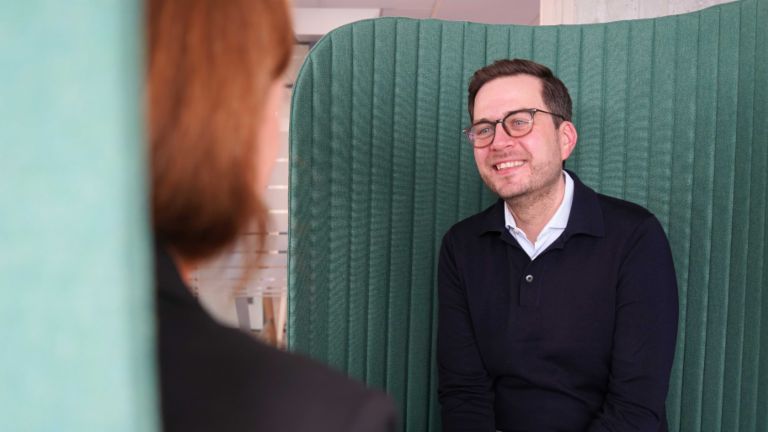 A man in an office environment in an interview situation.