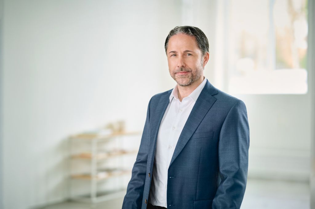 Portrait of Marwin Ramcke, Chairman of the EOS Group's Board of Directors in a bright room wearing a dark blazer 